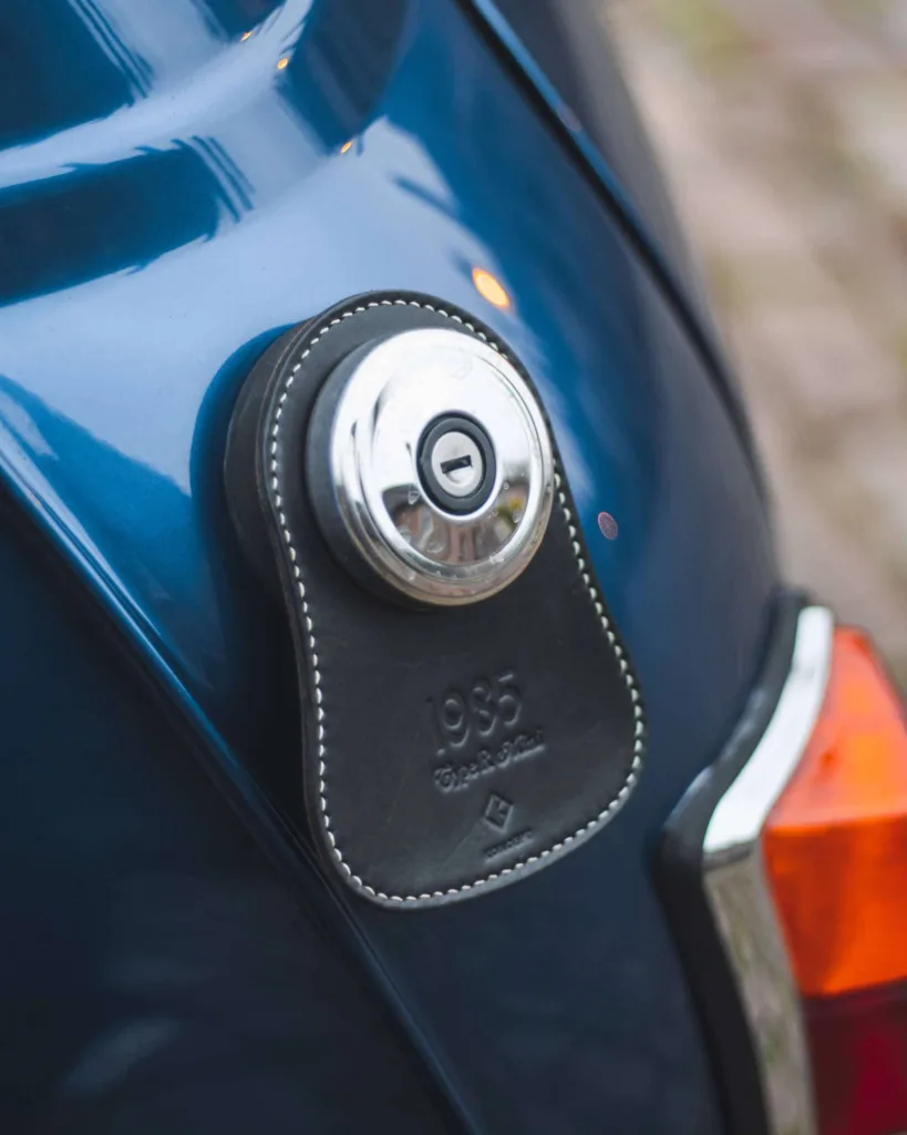 Koncept Studios black leather fuel bib with custom engraving installed on a blue classic Mini
