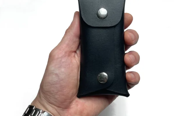 Hand holding a black leather pouch with snap button